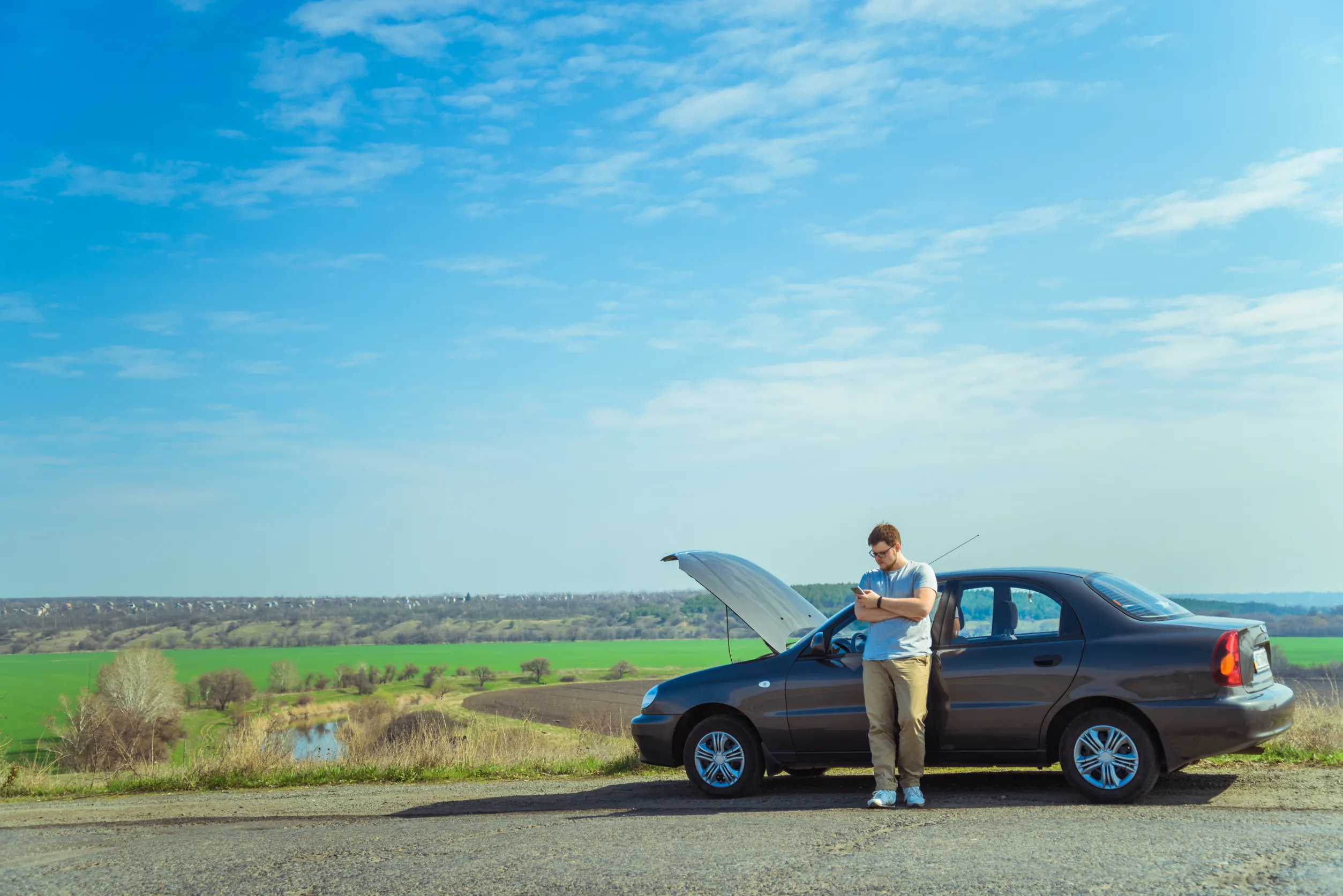 Man waiting on highway beside broken down car with wrong fuel issue in Sydney Man waiting on highway beside broken down car with wrong fuel issue in Sydney