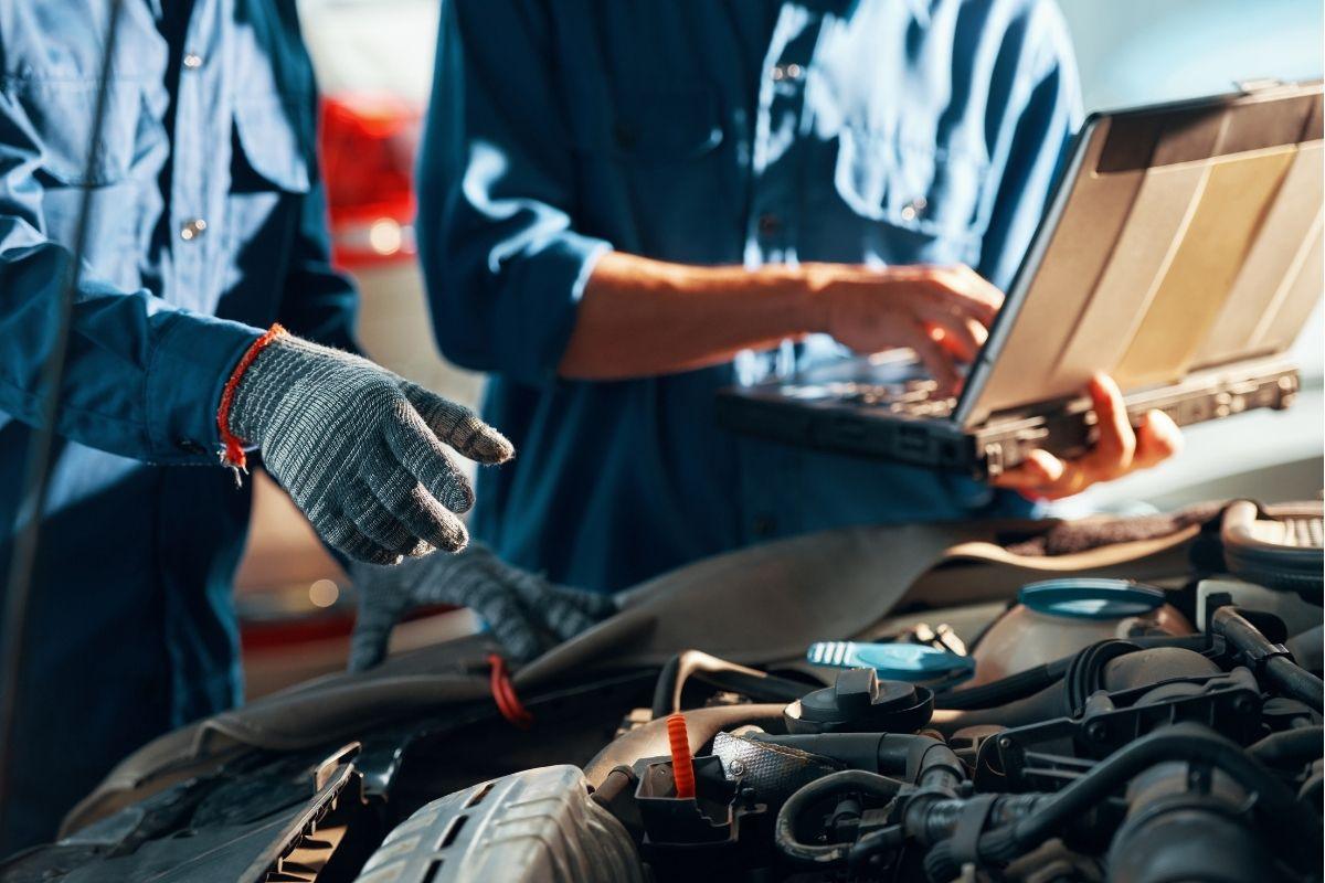 Mechanics diagnosing a vehicle engine using diagnostic tools in a workshop.