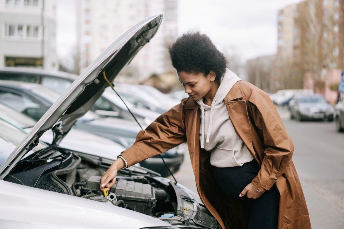 Woman checking car engine oil.